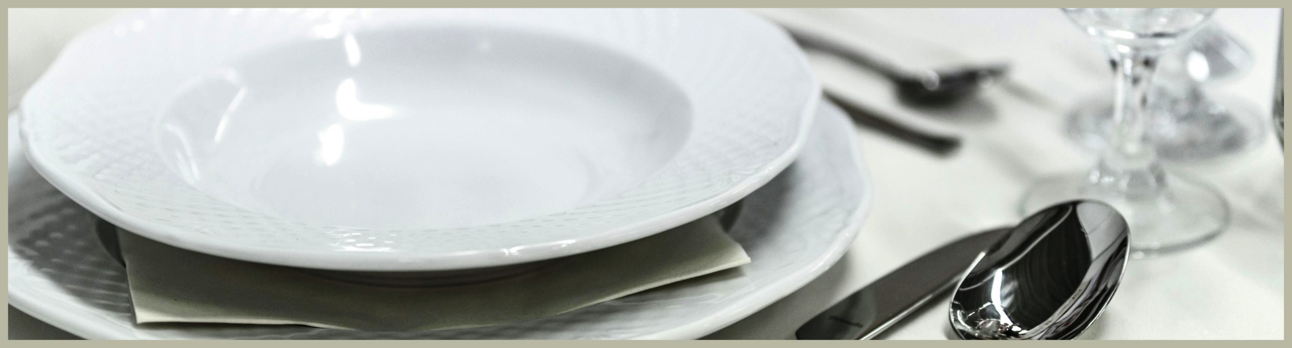 White soup bowl set on a white dinner plate in a cropped image of a table setting. This image heads the premium tableware page.